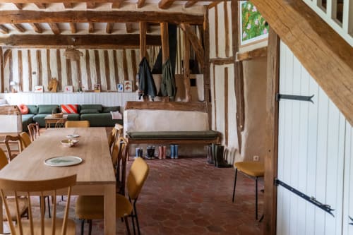 Salle à manger rustique aux Maisons Noisette avec poutres apparentes, tables en bois et assises vertes