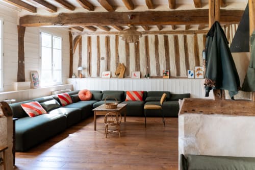 Salon rustique de la chambre d'hôtes Maisons Noisette avec poutres apparentes, canapé foncé et mobilier en bois