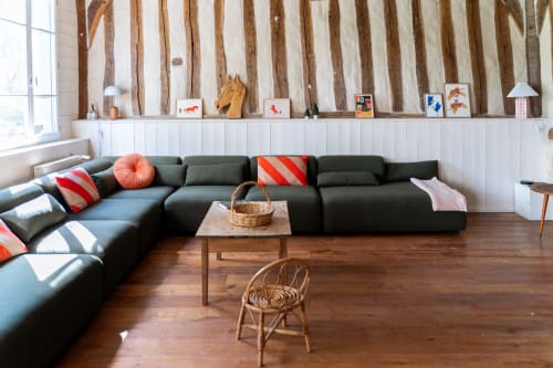 Salon moderne des Maisons Noisette avec canapé sectionnel courbe, accents bois et mur en poutres apparentes