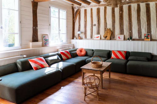 Salon moderne du gîte Maisons Noisette avec canapé sectionnel anthracite, poutres apparentes et décoration côtière
