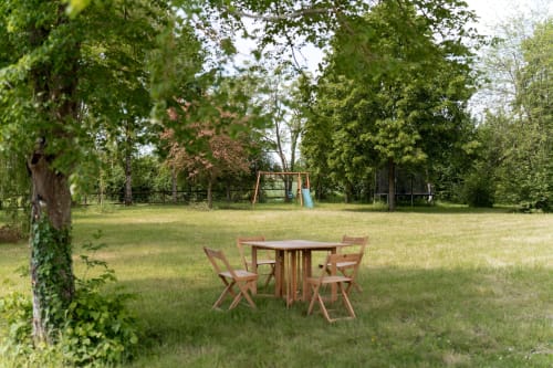 Table et chaises de pique-nique en bois dans le jardin verdoyant des Maisons Noisette, Saint-Pierre-des-Ormes
