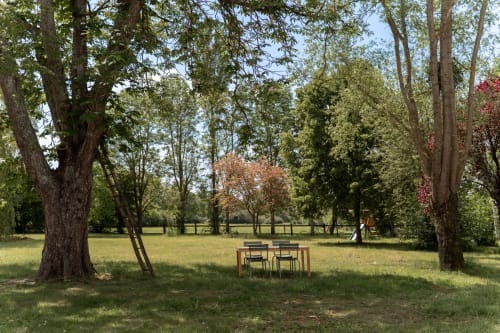 Ensemble table et chaises en bois sous de grands arbres dans le parc paisible de Maisons Noisette, Saint-Pierre-des-Ormes