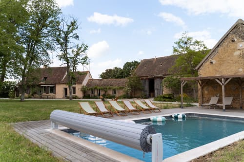 Espace piscine de Maisons Noisette avec transats, bâtisses en pierre et pelouse à Saint-Pierre-des-Ormes