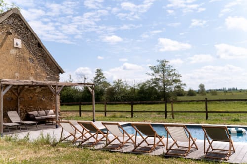 Piscine du gîte Maisons Noisette avec transats, pergola en bois et vue sur la campagne bucolique