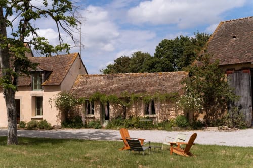 Cour de Maisons Noisette avec chaises Adirondack, bâtisses en pierre rustique et lierre à Saint-Pierre-des-Ormes