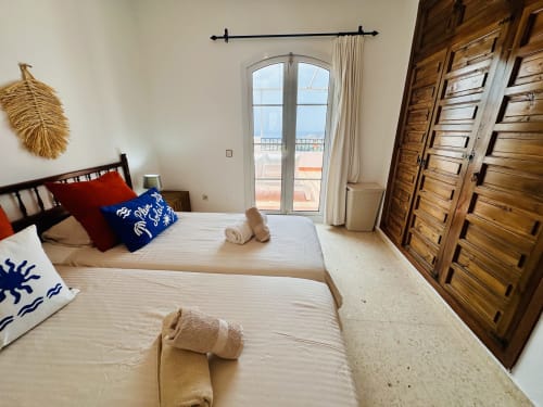 Dormitorio luminoso con balcón con vista al mar en Nerja Holiday Homes, camas gemelas, armarios de madera y terraza costera