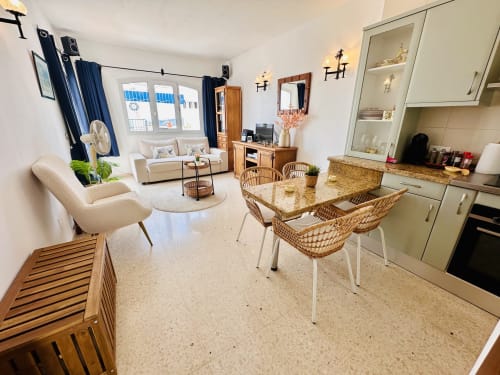 Moderno apartamento diáfano en Nerja con comedor, cocina y salón con sillas de mimbre y balcón con vistas al mar