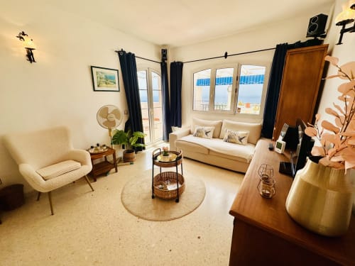 Luminoso apartamento con vistas al mar en Nerja, sofá color crema, sillón, muebles de madera y balcón con vistas al Mediterráneo