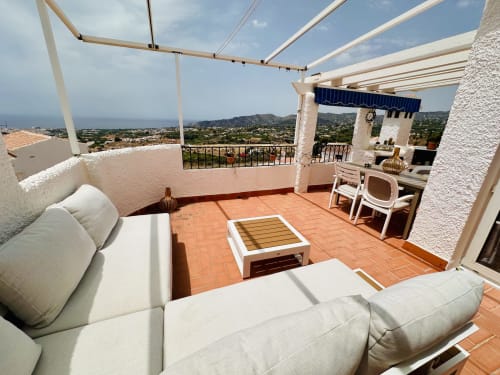 Amplia terraza con vistas al mar en apartamento exclusivo de Nerja, con cómoda sala de estar, pérgola y vistas a la costa