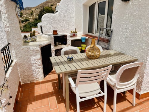 Zona de comedor en terraza de Nerja Holiday Homes con mesas, sillas, vistas a la montaña y paredes encaladas
