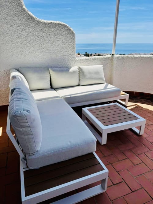 Sofá seccional blanco moderno y mesa en la terraza de Nerja Holiday Homes, con vistas al mar Mediterráneo y el paisaje costero