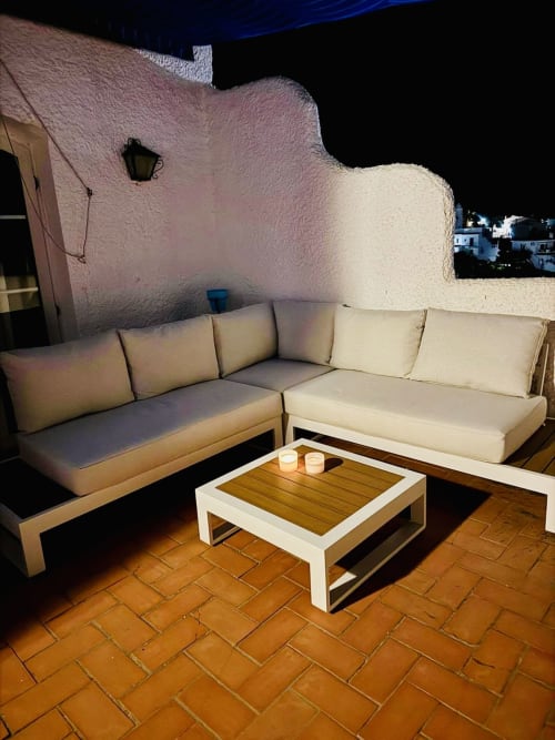 Zona de descanso exterior en tonos crema con sofá en L y mesa de café blanca en la terraza del apartamento Nerja Holiday Homes