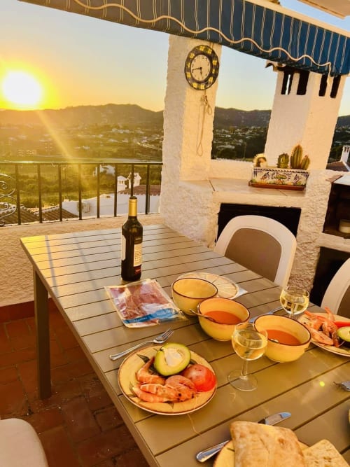 Cena al atardecer en la terraza exclusiva de apartamento con vistas al mar en Nerja, con vino, mariscos y paisaje mediterráneo