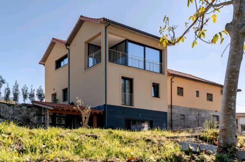 Serração House B&B em Rio Caldo - elegante fachada bege e azul com varanda vista para jardins verdes