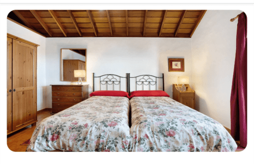 Dormitorio amplio en La Palma entre viñas y Teneguía con camas gemelas, vigas de madera y decoración rústica