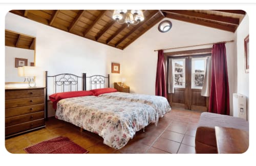 Amplio dormitorio en La Palma entre viñas y Teneguía con cama de hierro forjado, muebles de madera y suelo de barro cocido