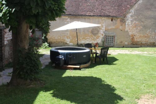 Bain à remous extérieur avec parasol blanc dans la cour du gîte Madiana 89 à Bellechaume