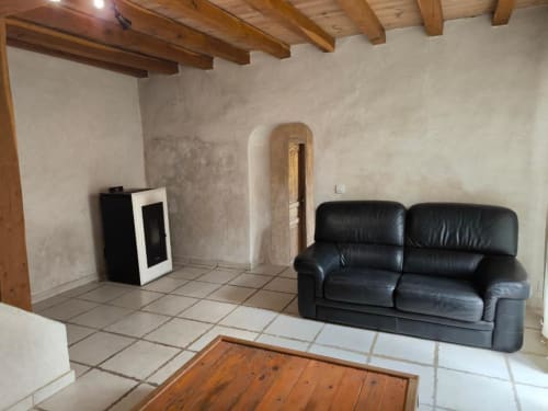 Salon rustique du gîte Madiana 89 à Bellechaume avec canapé cuir noir, poutres bois et arceau