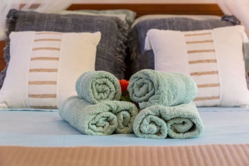 Serviettes roulées vertes avec fleur rouge sur le lit de l'hôtel Villas Amboise en Guadeloupe