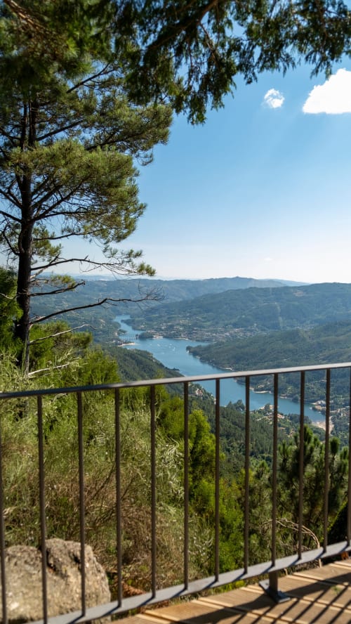 Terraço da Casa Serração com vista para a barragem de Rio Caldo e montanhas florestadas sob céu azul