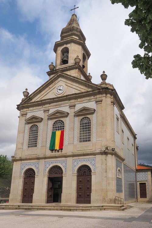 Igreja histórica de pedra com torre sineira e cruz em Rio Caldo, Portugal perto da Casa de Serração