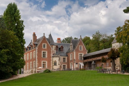 Château en briques rouges avec tourelles, pelouse soignée et bâtiments couverts de lierre aux Villas Amboise Guadeloupe
