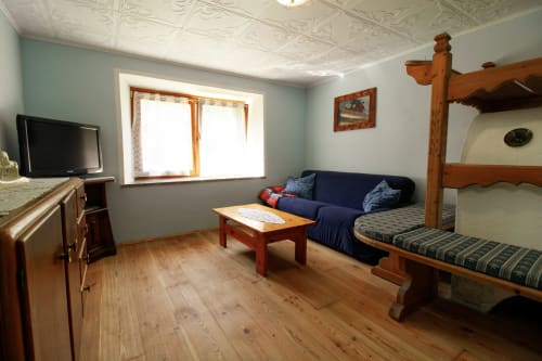 Gemütliches Apartmentschlafzimmer mit Etagenbett, Sofa, TV und Bergblick in Santo Stefano di Cadore