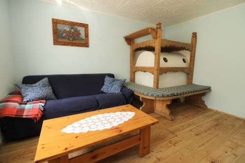 Gemütliches Wohnzimmer in Santo Stefano di Cadore mit dunkelblauem Sofa, Holzetagenbetten, Kiefertisch und Bergblick.
