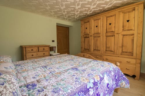 Geräumiges Schlafzimmer bei Mountains Properties in Santo Stefano di Cadore mit Möbeln aus Holz, floraler Bettwäsche und Dekorationen