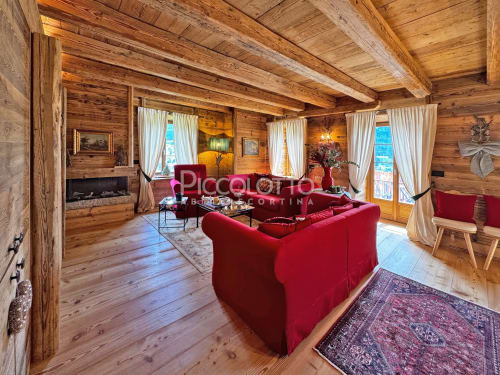 Lussuoso appartamento alpino in legno a Cortina d'Ampezzo con divano in velluto rosso, camino e vista sulle montagne