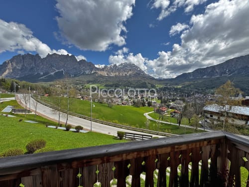 Balcone alpino con vista sulla valle di Cortina d'Ampezzo, le spettacolari cime delle Dolomiti e i verdi prati