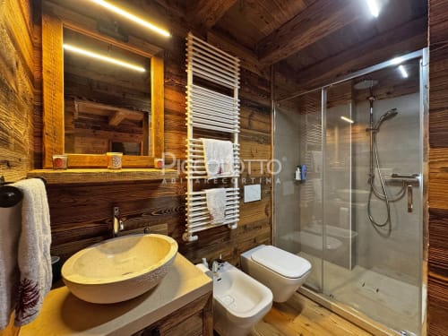 Bagno moderno in Alpen Maison, Cortina d'Ampezzo con pareti in legno, lavabo da appoggio, doccia in vetro, scaldasalviette