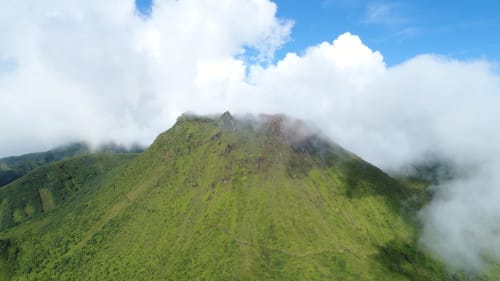 Pics montagneux verdoyants d'origine volcanique en Guadeloupe avec nuages brumeux et ciel bleu