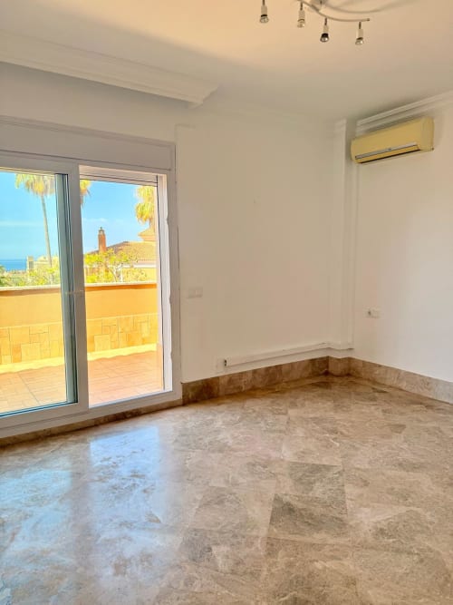 Dormitorio luminoso en BH Marbella con suelo de mármol, vistas al mar, acceso a terraza y aire acondicionado