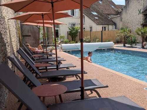 Chaises longues au bord de la piscine du Domaine de La Poule Noire avec parasols rouille et accès privé à la piscine