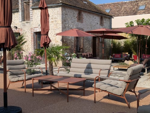 Élégante terrasse du Domaine de La Poule Noire avec bâtisses en pierre, parasols et vue sur les jardins