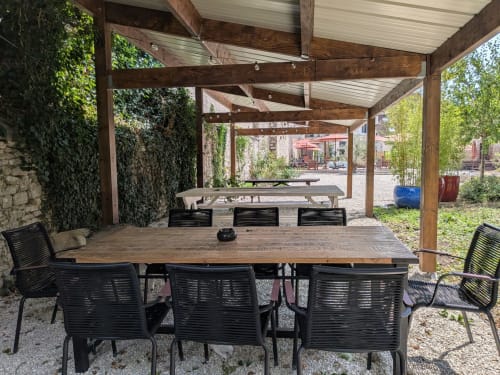 Salle à manger couverte avec table en bois, chaises noires et murs couverts de lierre au Domaine de La Poule Noire
