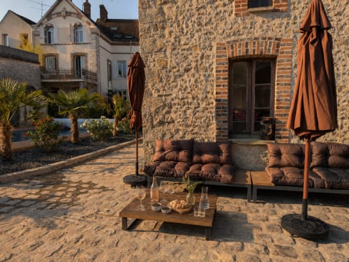 Cour ensoleillée en pierre au Domaine de La Poule Noire avec salon de détente, parasol et architecture rustique française