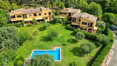 Vista aérea de la villa La Pastora en Llafranc, Palafrugell con piscina azul, casas de piedra amarilla y frondosos jardines