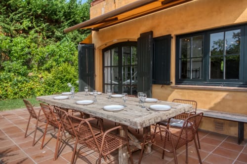 Patio de comedor al aire libre en la villa La Pastora en Llafranc, Palafrugell, con mesa de madera rústica y sillas de terracota