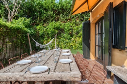 Mesa de comedor exterior lista para la cena en la terraza de la villa Finques Garcia Enrich en Palafrugell, España, con sombrilla naranja