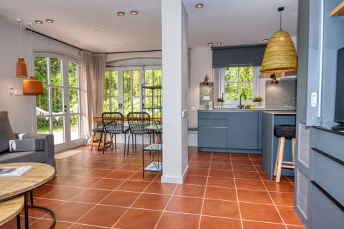 Cocina y comedor de villa moderna en Palafrugell con mueblería azul, baldosas de barro y acceso a patio exterior