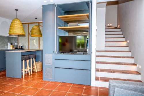 Cocina moderna con gabinetes azules, luces colgantes tejidas y escaleras de madera en villa en Llafranc, Palafrugell