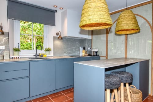Cocina moderna con armarios azules, luces colgantes tejidas e isla de mármol en la villa La Pastora en Llafranc, Palafrugell