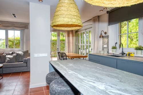Cocina moderna con isla en la villa La Pastora, Llafranc, con luminarias de paja y vistas al área de estar
