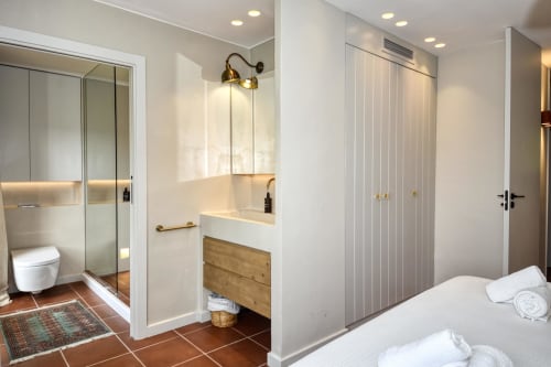 Baño moderno de villa en Palafrugell con ducha abierta, tocador de madera y acceso a vista de piscina