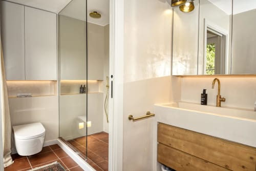 Baño moderno en villa Llafranc con accesorios de latón, tocador blanco, ducha abierta y detalles de madera