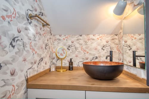 Moderno lavabo con lavamanos de piedra negra en la villa de Llafranc, decorado con papel pintado floral