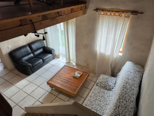 Séjour de la maison de vacances Madiana 89 à Bellechaume avec canapé en cuir, sièges à motifs, table basse en bois et lumineux