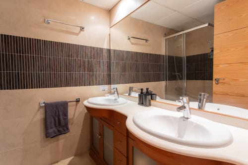 Modern bathroom with double sink vanity, striped tile walls, and rainfall showerhead at Haus Holiday Homes in San Pedro del